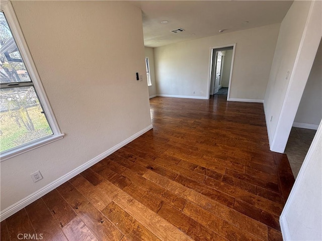 spare room with dark wood-type flooring, baseboards, and plenty of natural light