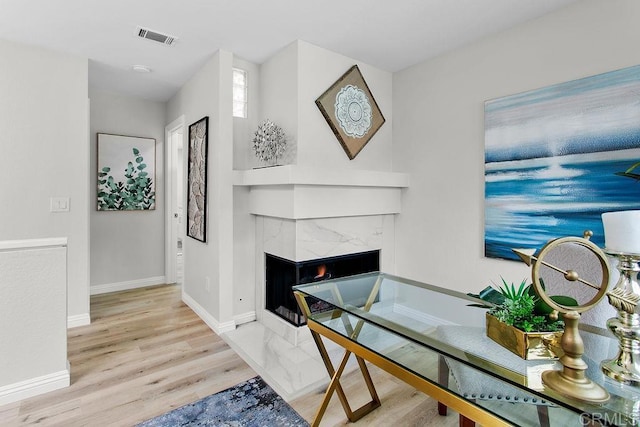 office area with light wood-style flooring, baseboards, and a premium fireplace