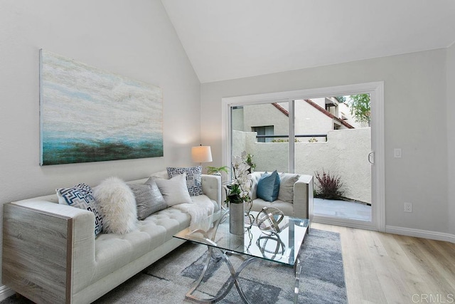 living area featuring wood finished floors, vaulted ceiling, and baseboards