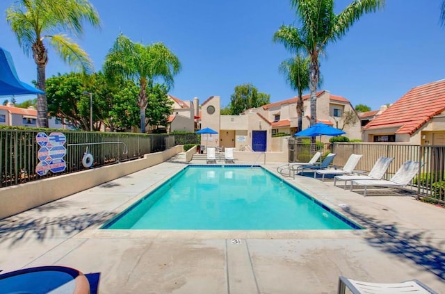 community pool featuring fence, a patio area, and a residential view