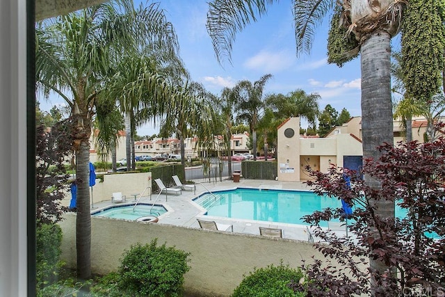 community pool with a community hot tub, fence, and a patio area
