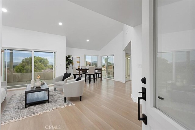 living room with light wood-type flooring, recessed lighting, and high vaulted ceiling