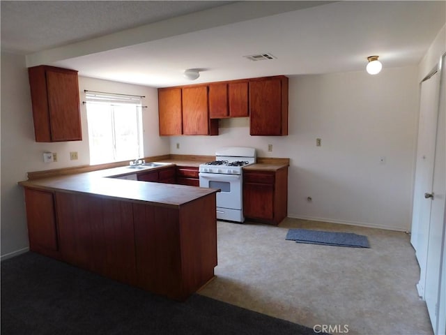 38625 25th St E, Palmdale, CA 93550 - kitchen featuring white range with gas stovetop, a peninsula, a sink, light carpet, and brown cabinets