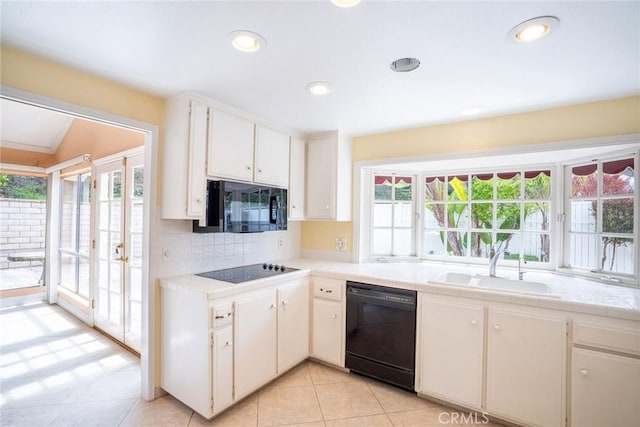 kitchen with black appliances, a sink, tile countertops, tasteful backsplash, and light tile patterned floors