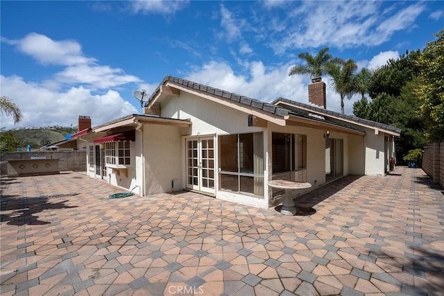 back of house featuring stucco siding, a chimney, a patio area, french doors, and fence