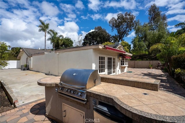 view of patio / terrace featuring exterior kitchen, a grill, a fenced backyard, and french doors