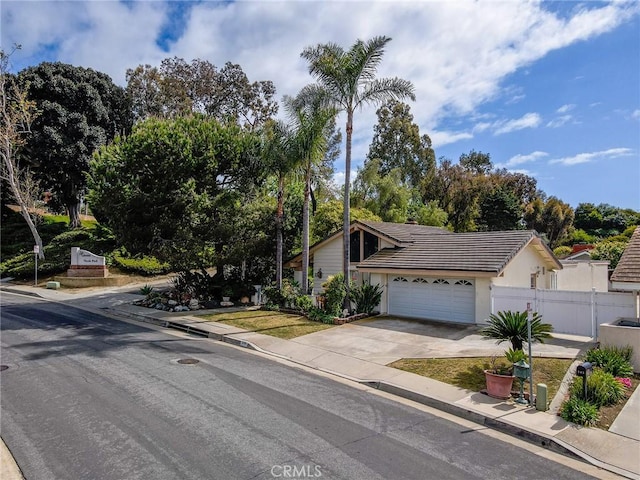 view of front of home with fence, driveway, a tile roof, stucco siding, and an attached garage