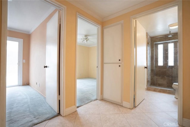 hallway featuring crown molding, light tile patterned floors, plenty of natural light, and baseboards