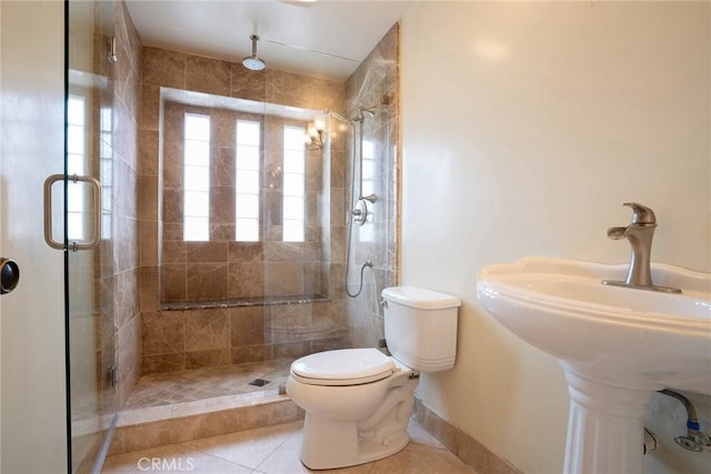 bathroom featuring a stall shower, tile patterned floors, toilet, and baseboards