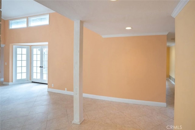 spare room featuring ornamental molding, healthy amount of natural light, baseboards, and light tile patterned floors