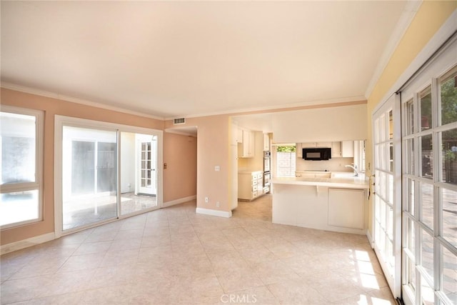 unfurnished living room featuring ornamental molding, baseboards, plenty of natural light, light tile patterned flooring, and a sink