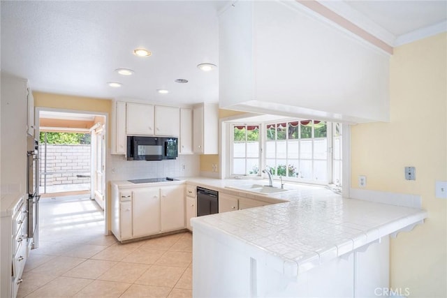 kitchen featuring black appliances, a sink, a peninsula, backsplash, and light tile patterned floors