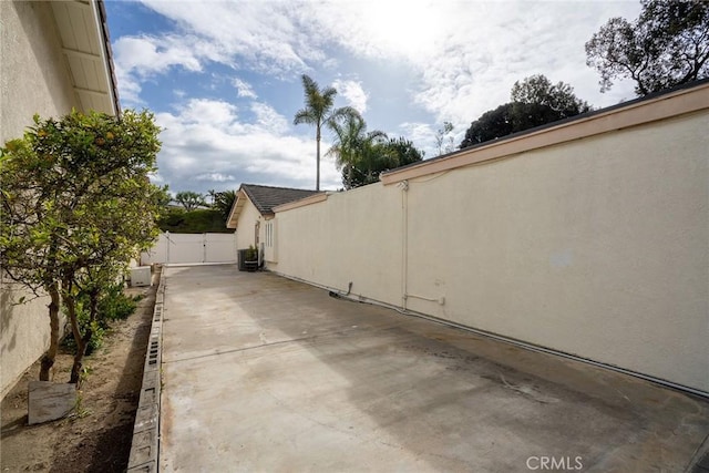 view of property exterior with stucco siding, a patio area, fence, and central AC