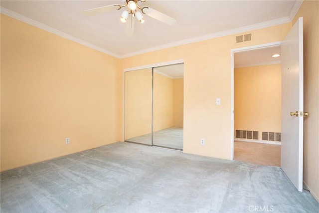 unfurnished bedroom with carpet floors, crown molding, a closet, and a ceiling fan