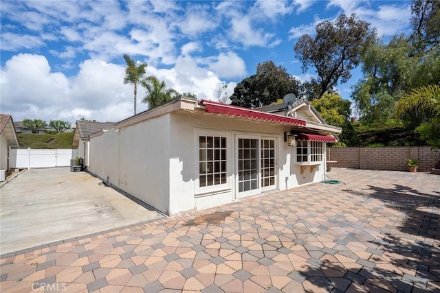 back of property with stucco siding, fence, a patio area, and a tile roof