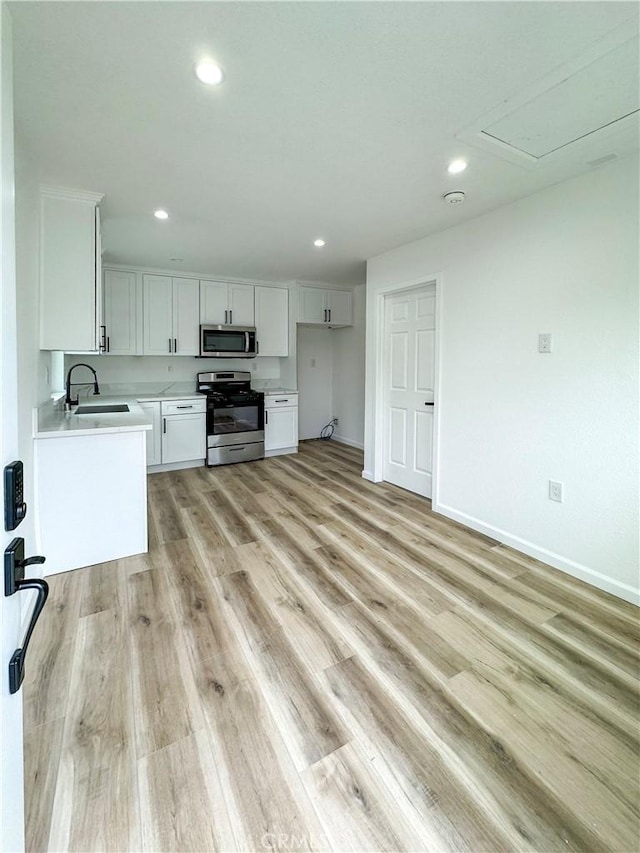 10430 Densmore Ave, Granada Hills, CA 91344 - kitchen featuring stainless steel appliances, a sink, white cabinets, light countertops, and light wood-type flooring