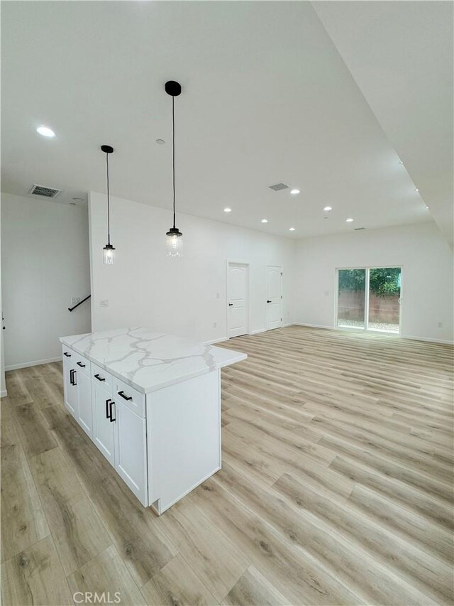 10430 Densmore Ave, Granada Hills, CA 91344 - kitchen featuring open floor plan, light wood-type flooring, light stone countertops, white cabinets, and a center island