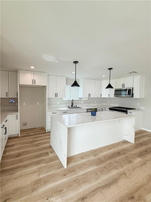 10430 Densmore Ave, Granada Hills, CA 91344 - kitchen featuring stainless steel microwave, a sink, a center island, stove, and white cabinetry