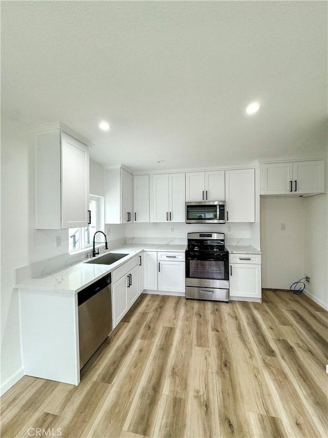 10430 Densmore Ave, Granada Hills, CA 91344 - kitchen with appliances with stainless steel finishes, a sink, white cabinetry, light wood-type flooring, and recessed lighting