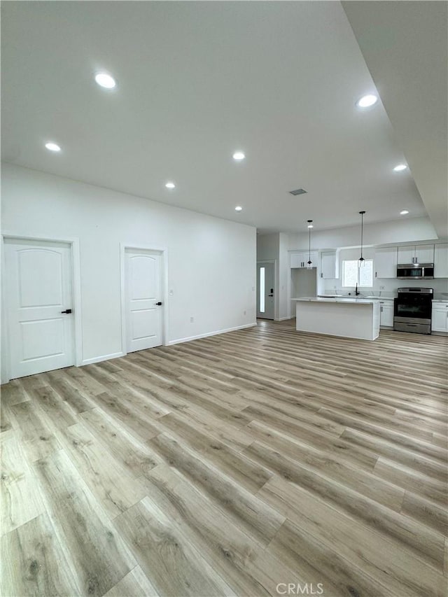 10430 Densmore Ave, Granada Hills, CA 91344 - unfurnished living room featuring light wood-type flooring, recessed lighting, a sink, and baseboards