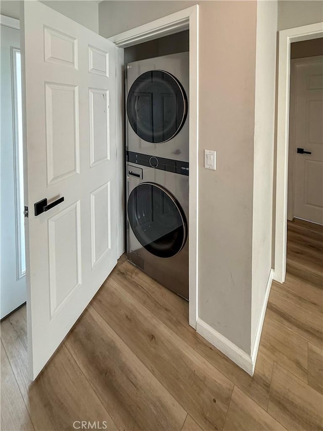 10430 Densmore Ave, Granada Hills, CA 91344 - laundry room with stacked washer and clothes dryer, wood finished floors, and baseboards