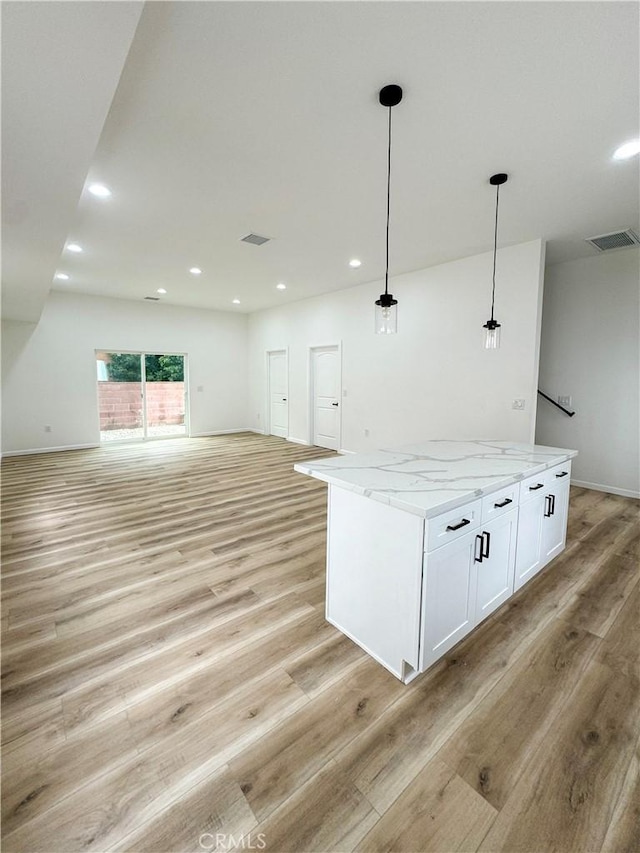 10430 Densmore Ave, Granada Hills, CA 91344 - kitchen featuring open floor plan, light wood-style flooring, white cabinets, light stone counters, and hanging light fixtures
