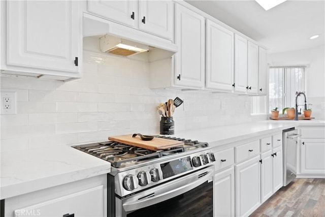 kitchen with appliances with stainless steel finishes, a sink, under cabinet range hood, and white cabinetry