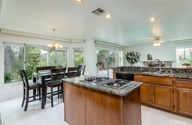 21714 Agajanian Ln, Saugus, CA 91350 - kitchen with a sink, stainless steel gas stovetop, black dishwasher, a center island, and brown cabinetry