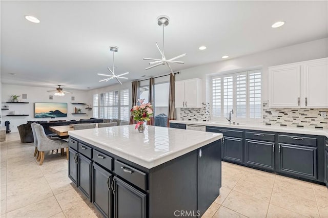 kitchen with a sink, ceiling fan, white cabinetry, tasteful backsplash, and tile counters