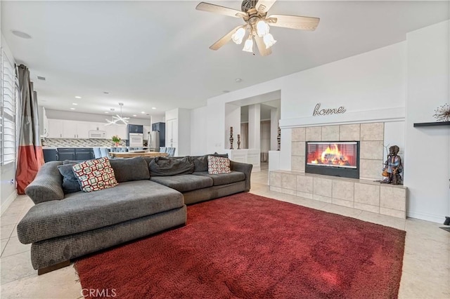 living room with light tile patterned floors, a ceiling fan, a tile fireplace, recessed lighting, and baseboards