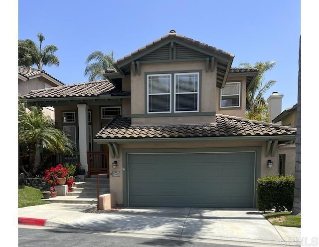 view of front of house with an attached garage, a tiled roof, driveway, and stucco siding