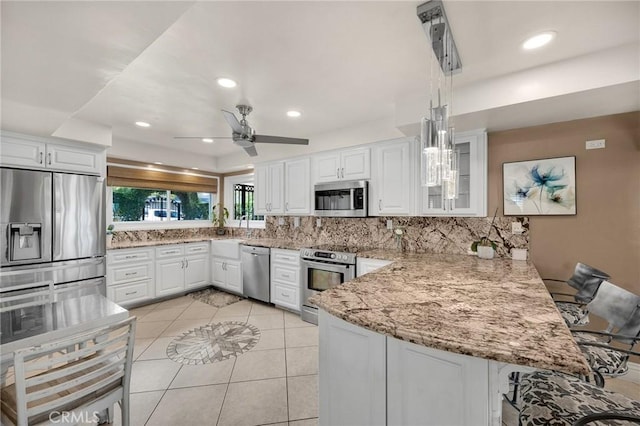 kitchen featuring appliances with stainless steel finishes, a peninsula, backsplash, white cabinets, and recessed lighting