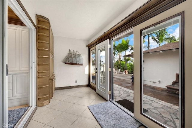 doorway featuring plenty of natural light, light tile patterned floors, baseboards, and stairs