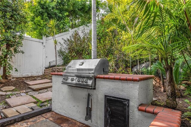 view of patio / terrace with area for grilling, fence, and an outdoor kitchen