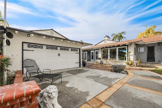ranch-style home featuring stucco siding, concrete driveway, a garage, and a chimney