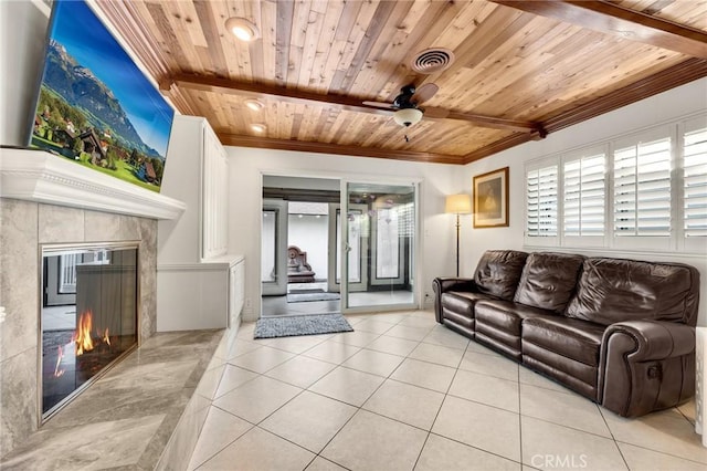 living area featuring wooden ceiling, light tile patterned flooring, a ceiling fan, ornamental molding, and a fireplace