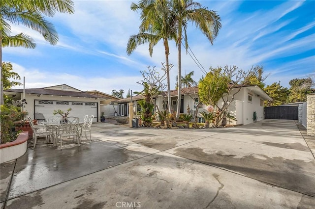 ranch-style home featuring stucco siding, concrete driveway, fence, and an attached garage