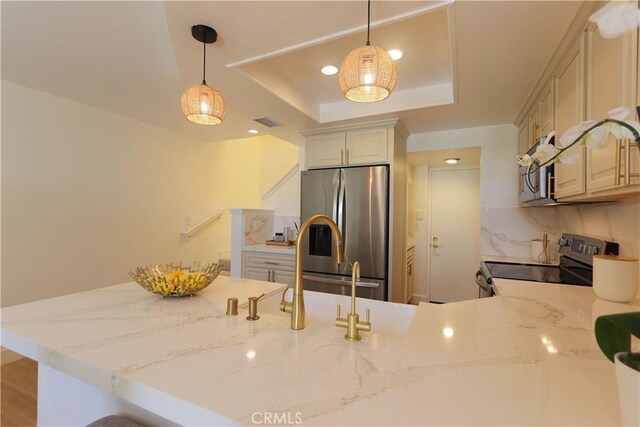 kitchen featuring stainless steel appliances, a raised ceiling, a peninsula, light stone countertops, and recessed lighting