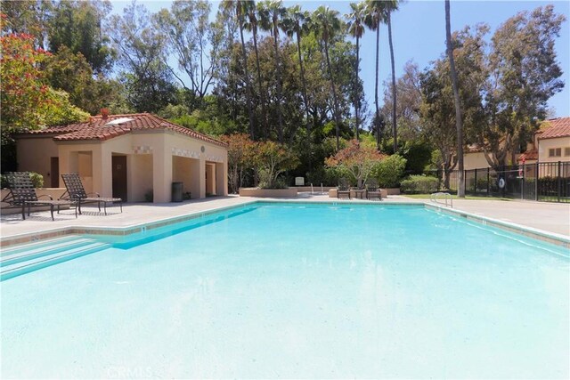 community pool with fence and a patio