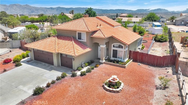 15199 Farmington Ct, Hesperia, CA 92345 - mediterranean / spanish-style home featuring a tile roof, stucco siding, fence, an attached garage, and a mountain view