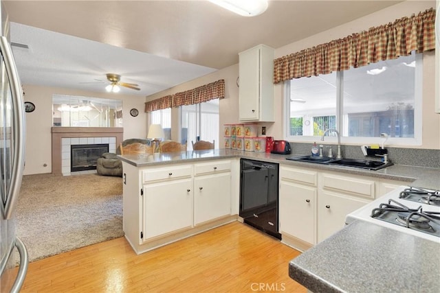 15199 Farmington Ct, Hesperia, CA 92345 - kitchen featuring black dishwasher, a sink, a tiled fireplace, and light wood-style floors