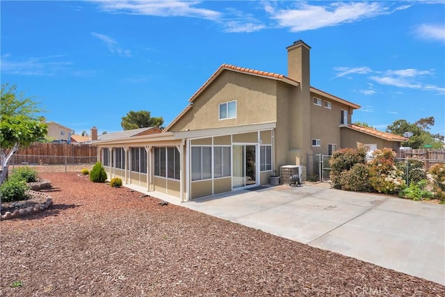 15199 Farmington Ct, Hesperia, CA 92345 - rear view of house featuring a sunroom, a chimney, a fenced backyard, stucco siding, and a patio