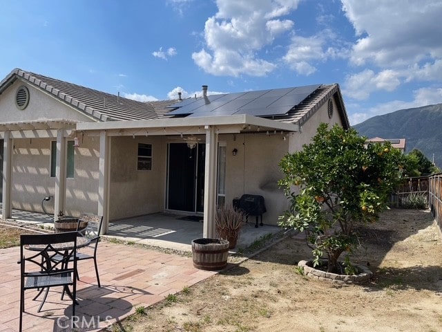 124 Lighthouse Ct, San Jacinto, CA 92583 - back of house featuring stucco siding, a fenced backyard, solar panels, and a pergola