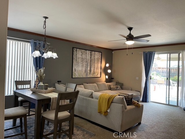 124 Lighthouse Ct, San Jacinto, CA 92583 - carpeted dining space with a ceiling fan, plenty of natural light, a chandelier, and crown molding