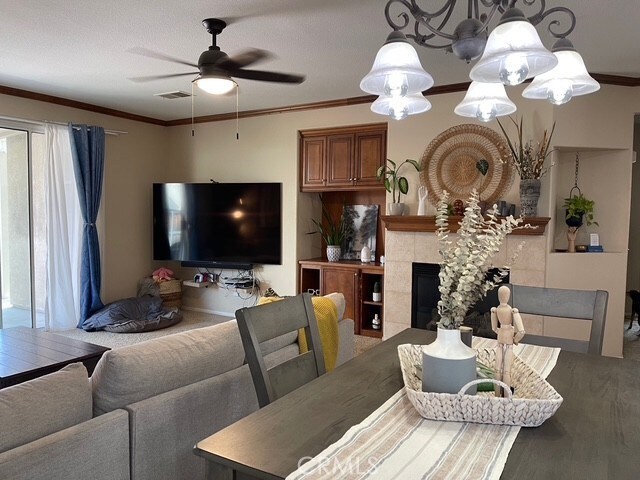 124 Lighthouse Ct, San Jacinto, CA 92583 - dining area with a ceiling fan, crown molding, wood finished floors, and a fireplace