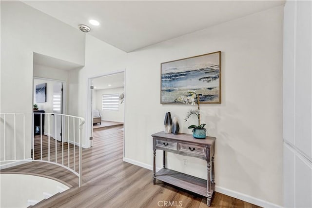 hallway featuring baseboards, wood finished floors, and recessed lighting
