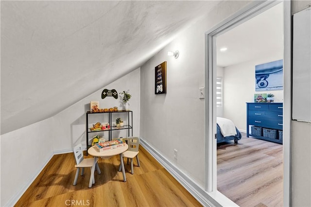 interior space featuring wood finished floors, lofted ceiling, and baseboards