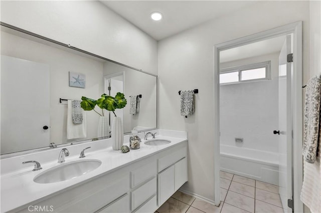 full bath featuring double vanity, a bathtub, baseboards, and tile patterned flooring