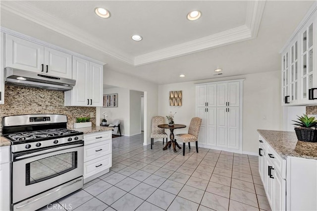 kitchen with gas stove, under cabinet range hood, a raised ceiling, decorative backsplash, and recessed lighting