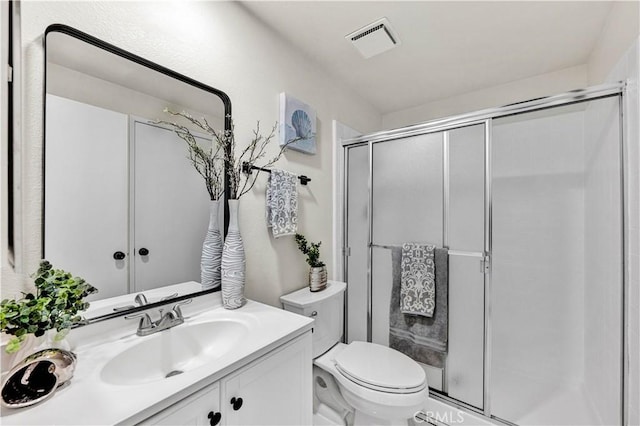 full bathroom featuring a stall shower, toilet, and vanity